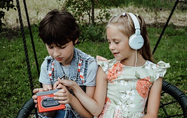 dzieci na dworze słuchające muzyki przez słuchawki